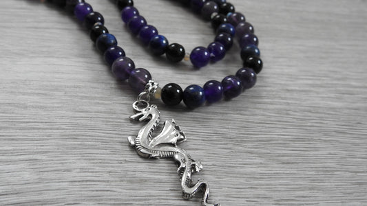 Handcrafted dragon pendant in sterling silver featuring blue lapis lazuli, amethyst, obsidian, and opal stones, front view against white background.