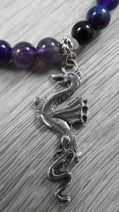 Profile view of handcrafted dragon pendant displaying sterling silver texture work, antique silver accents, and semi-precious stone integration.