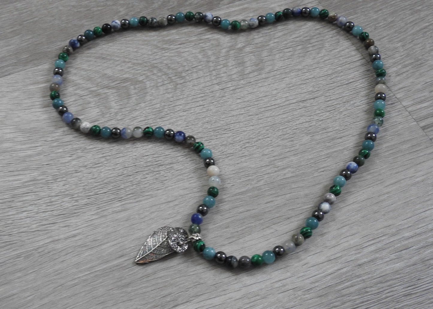 Side profile view of handcrafted sterling silver leaf and coral pendant showing three-dimensional organic form and texture blend.