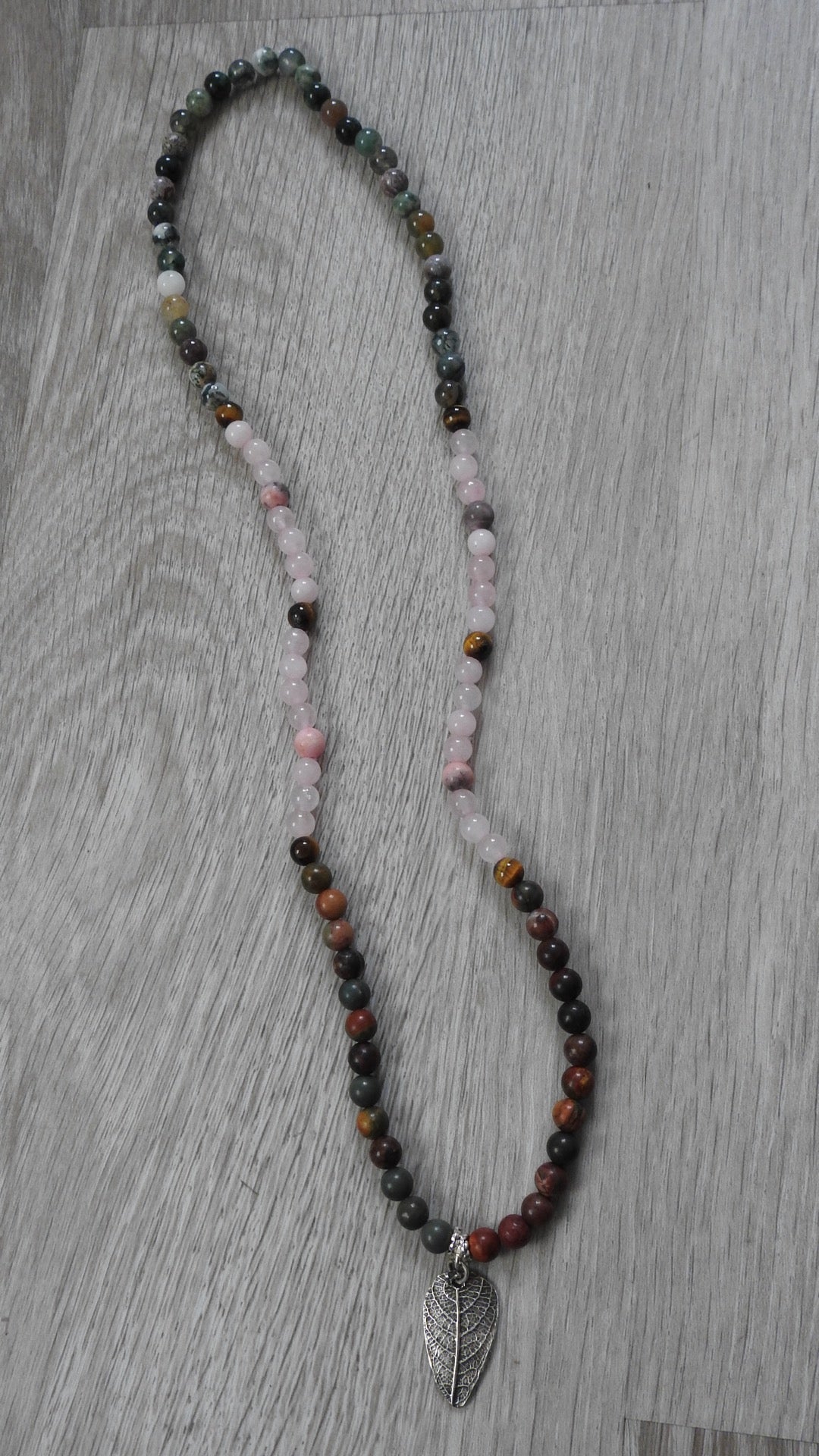 Close-up detail of sterling silver leaf pendant showing vibrant Diwali-inspired gemstones including rose quartz and Indian agate.