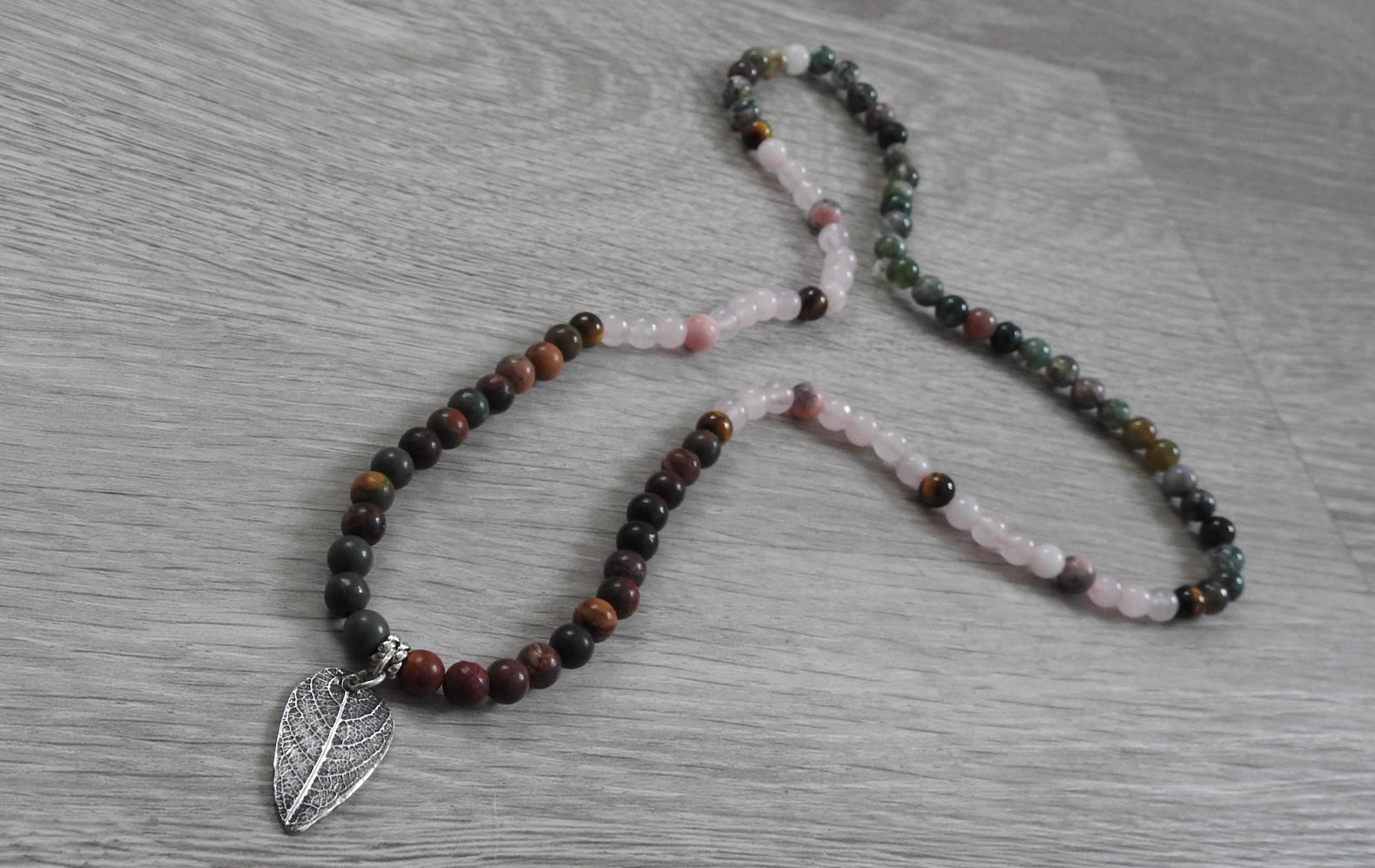 Macro detail of authentic leaf texture impressed into sterling silver pendant with yellow tiger eye and pink zebra stone accents.