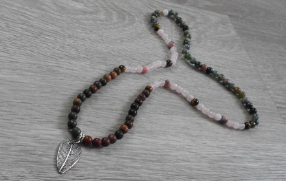 Macro detail of authentic leaf texture impressed into sterling silver pendant with yellow tiger eye and pink zebra stone accents.