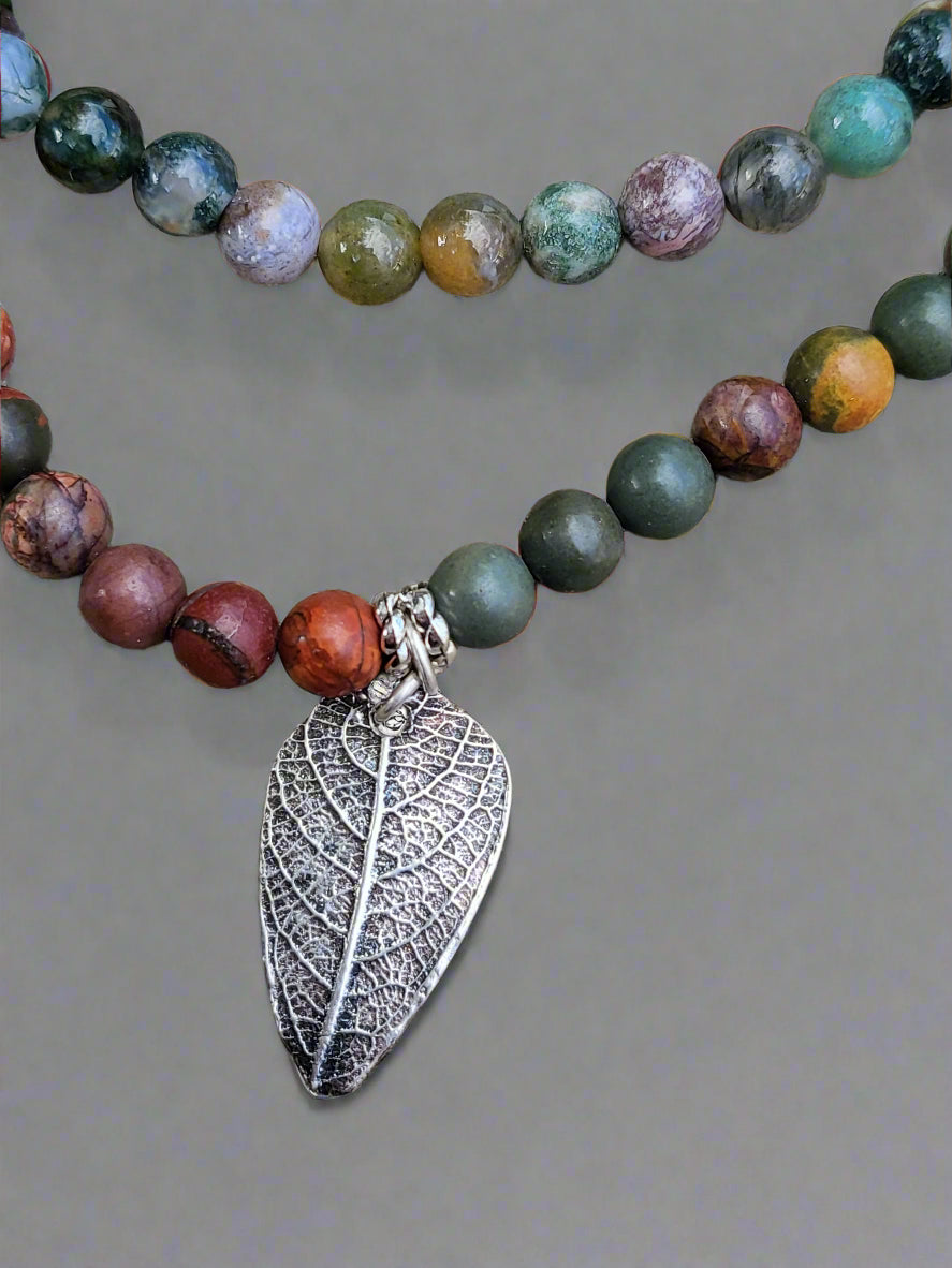 Lifestyle photograph of sterling silver leaf pendant necklace displayed in natural woodland setting.