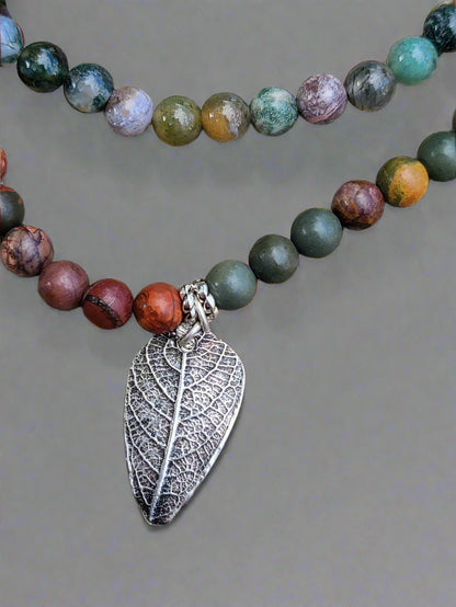 Lifestyle photograph of sterling silver leaf pendant necklace displayed in natural woodland setting.