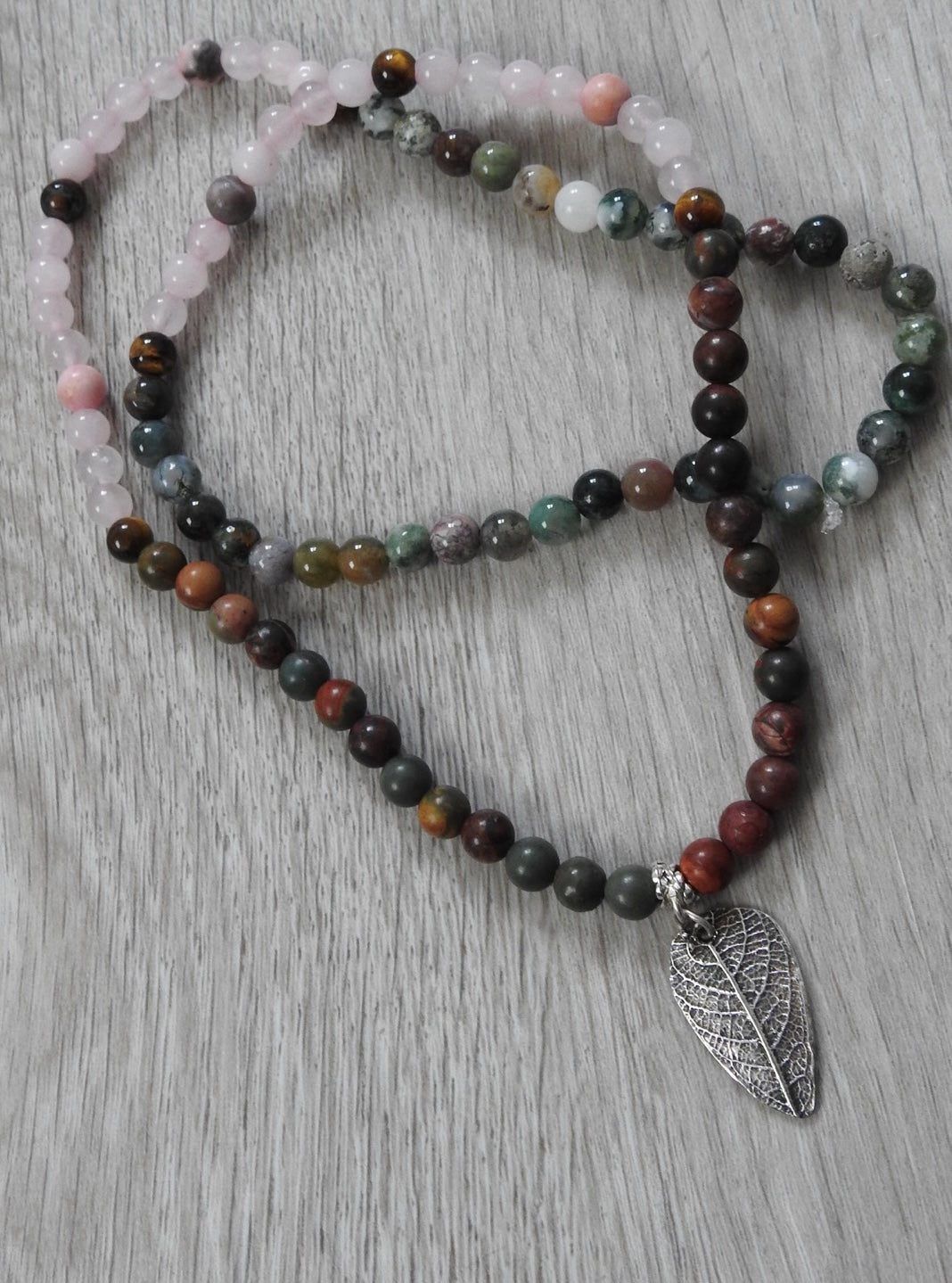 Angled view of sterling silver leaf pendant showcasing community-inspired design with rose quartz, tiger eye, and cultural colour palette.