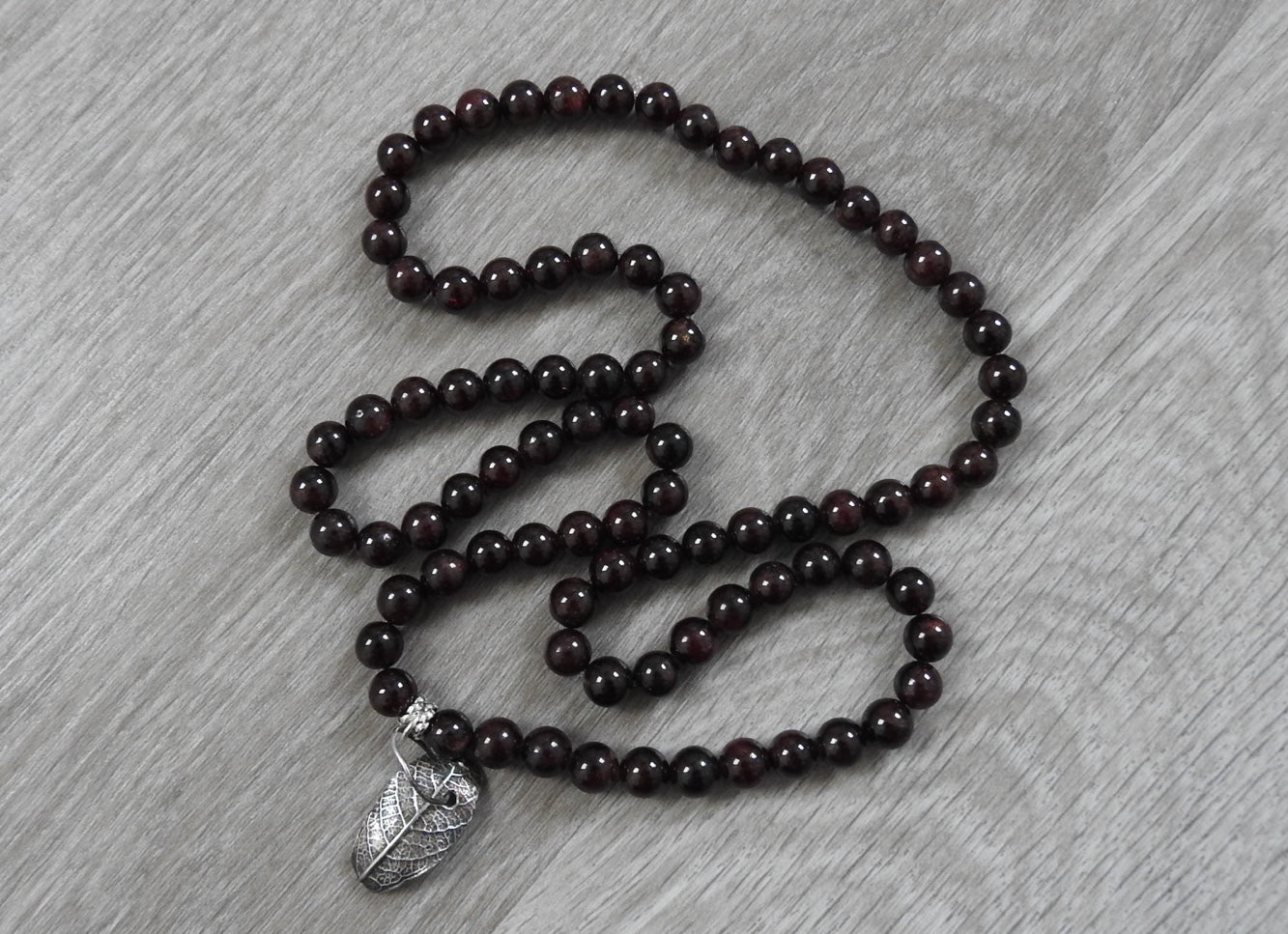 Close-up detail of sterling silver rustic leaf pendant showing garnet stone placement and authentic leaf texture with antique silver finish.