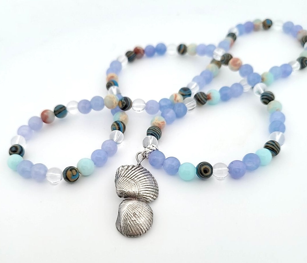 Professional profile view of sterling silver sea shell pendant showcasing complete dimensional craftsmanship and coastal-inspired design with blue gemstones.