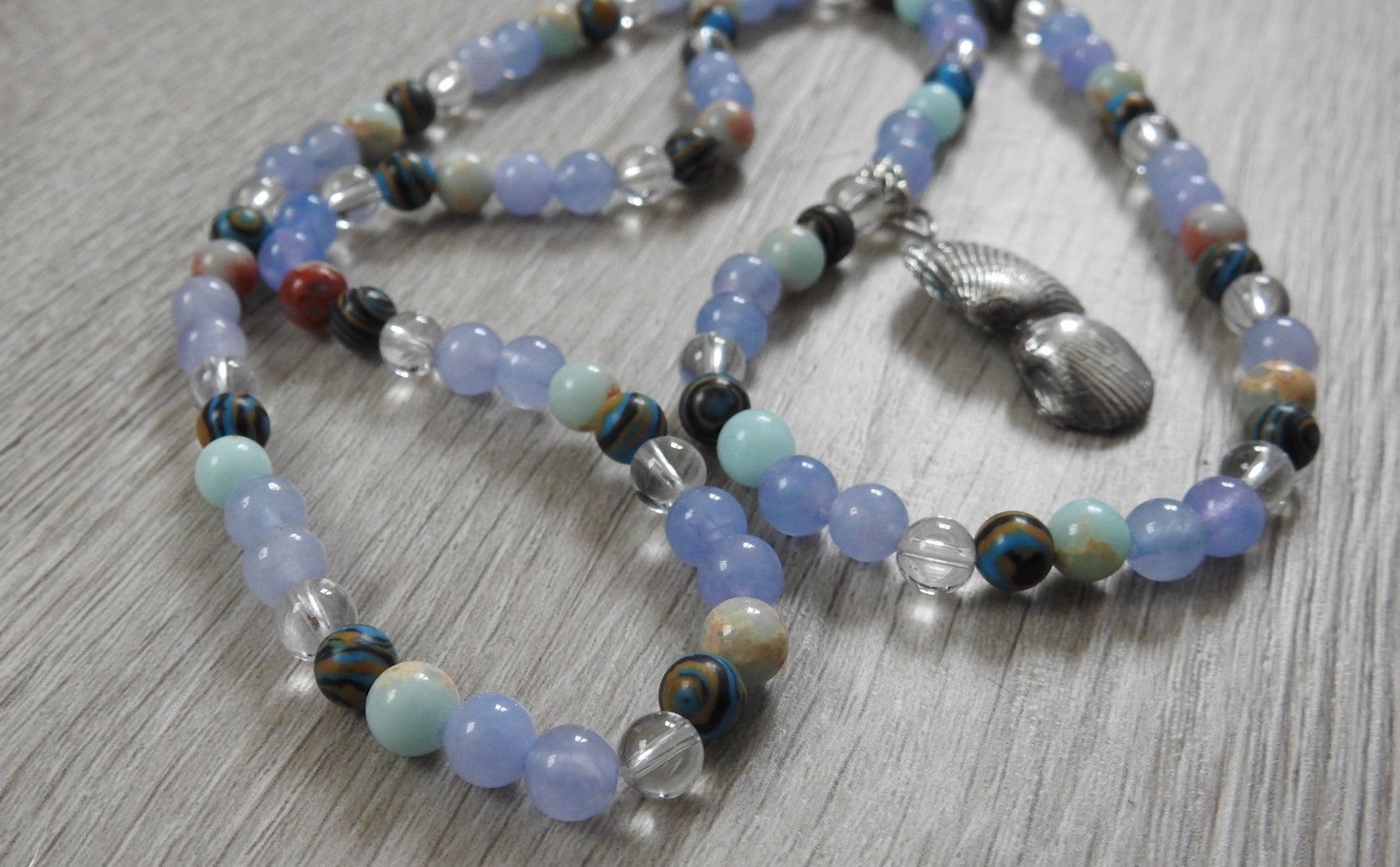 Angled view of sterling silver sea shell pendant showcasing authentic shell texture and ocean-inspired gemstone arrangement.