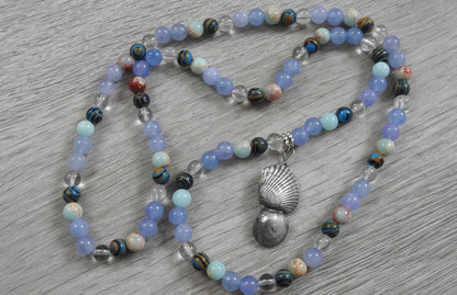 Lifestyle photograph of sterling silver sea shell pendant displayed in coastal setting highlighting ocean treasures inspiration.