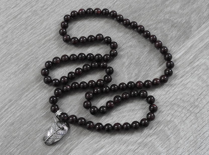 Front view of handcrafted sterling silver leaf pendant with garnet stones showing unique leaf impression and rustic organic design.